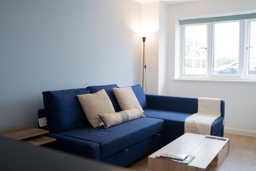 a blue couch in a living room with a table at The Kensington Apartment, FREE CarPark, Ideal Location for exploring Oxford City & nearby places, easy access to ring road MINI PLANT, Universities & Oxford Science Parks in Oxford