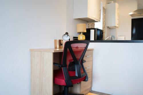a red chair sitting at a counter in a kitchen at The Kensington Apartment, FREE CarPark, Ideal Location for exploring Oxford City & nearby places, easy access to ring road MINI PLANT, Universities & Oxford Science Parks in Oxford