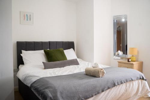 a bedroom with a bed with white and green pillows at The Kensington Apartment, FREE CarPark, Ideal Location for exploring Oxford City & nearby places, easy access to ring road MINI PLANT, Universities & Oxford Science Parks in Oxford