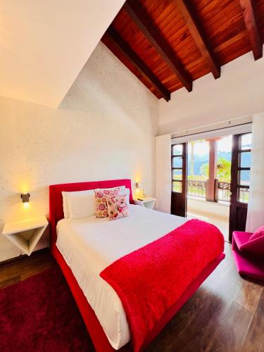 a bedroom with a large bed with a red blanket at Hotel Reserva Monarca in Salento
