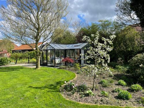 a garden with a black greenhouse in a yard at KorenGastvrij in Noordbroek