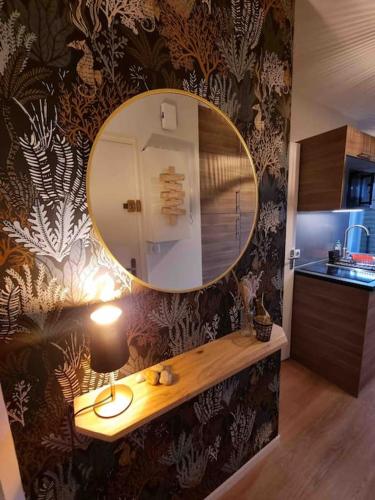 La salle de bains est pourvue d'un miroir et d'une table avec une lampe. dans l'établissement Appartement bord de mer, à Dinard