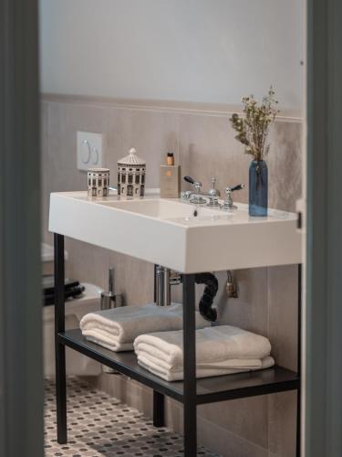 La salle de bains est pourvue d'un lavabo et de serviettes sur une étagère. dans l'établissement Villa Berry Centre Deauville - Chic & Stylée - Magnifique Jardin, à Deauville