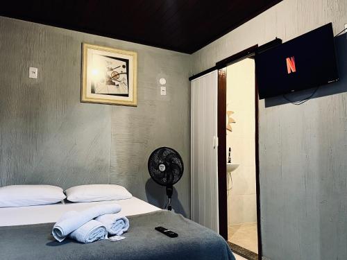 a room with a bed and a fan and a bathroom at Espaço Verano - Suítes in Niterói