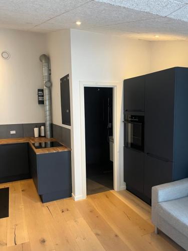 a kitchen with black cabinets and a black refrigerator at Central lejlighed in Herning