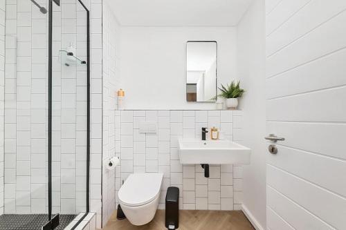 a white bathroom with a toilet and a sink at Chic Minimalist City Retreat in Cape Town