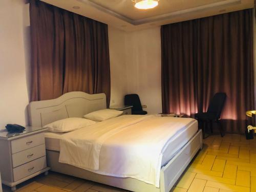 a bedroom with a large white bed and two chairs at فندق اربد بلازا in Irbid