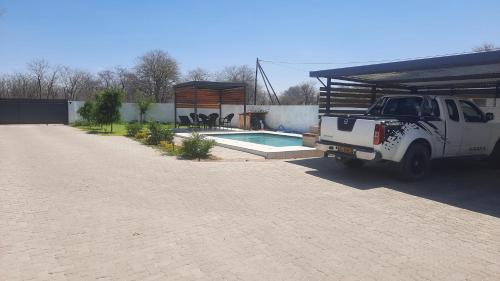 a white truck parked in a driveway next to a pool at Rocksie Apartments in Maun