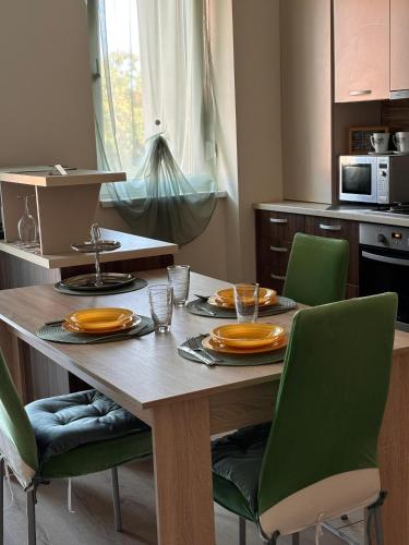 a dining room table with green chairs and a kitchen at Mirvana Apartments Serenity Suite in Timişoara