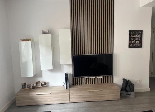 a living room with a television on a wooden entertainment center at Apartamento Ángela in Gijón