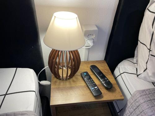 a table with a lamp and two remote controls on it at Villa Bilac - Amplos Studios 2km da Vila Germânica in Blumenau