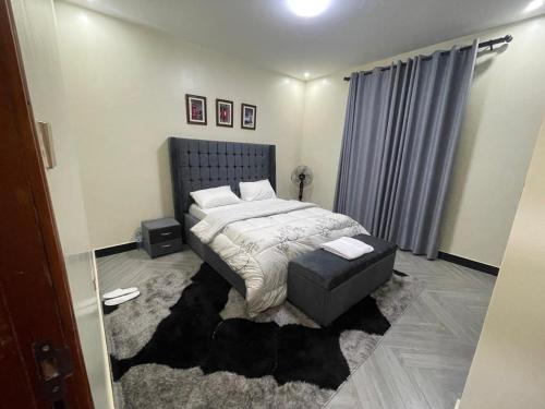 Un dormitorio con una cama y una otomana en una habitación. en Luxury Budgethomes Bukoto, en Kampala