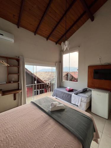 a bedroom with two beds and a large window at Pousada Estrelas no Mar Florianópolis in Florianópolis