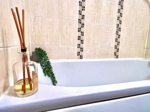 a white bath tub with a bottle and a plant in it at Bibis Home - Hertford in Hertford