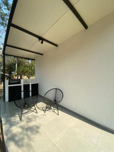 two chairs sitting on a patio with a white wall at Posada San Miguel in Paraguarí