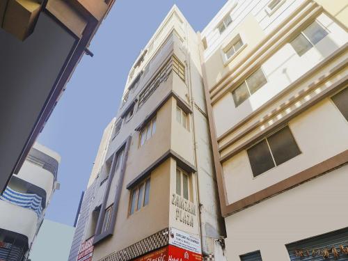 a tall white building next to a building at Hotel O Aroma Classic Near Nampally Railway station in Hyderabad