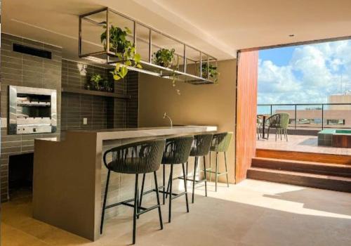 una cucina con un bar con sgabelli e un balcone di Praia de Cabo Branco - Espaço Privativo - Conforto - Lazer - Luxo a João Pessoa