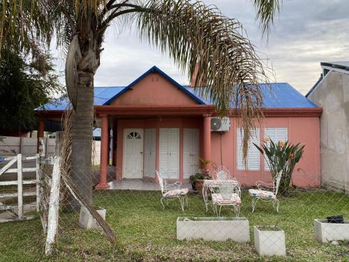 Una casa rosa con sillas y una palmera. en Alquiler Villa Elisa, en Villa Elisa