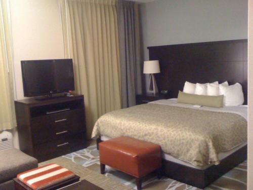 a hotel room with a bed and a flat screen tv at Staybridge Suites Houston Stafford - Sugar Land by IHG in Stafford