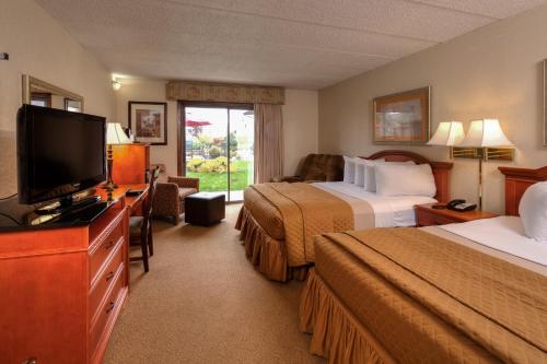 a hotel room with two beds and a flat screen tv at The Foothills Inn in Rapid City