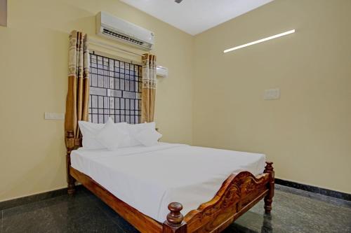 a bedroom with a bed with white sheets and a window at Super Hotel O Vsv Guest House in Chennai
