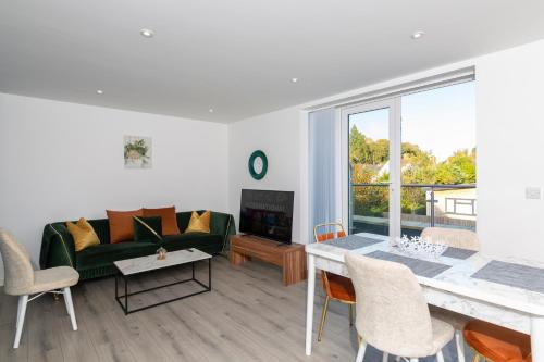 Una sala de estar con un sofá verde y una mesa. en The Lincoln Apartment 2023 NEW-BUILD, 1 mintue walk JR John Radcliffe Hospital & Ideal for Oxford Brookes University, en Oxford