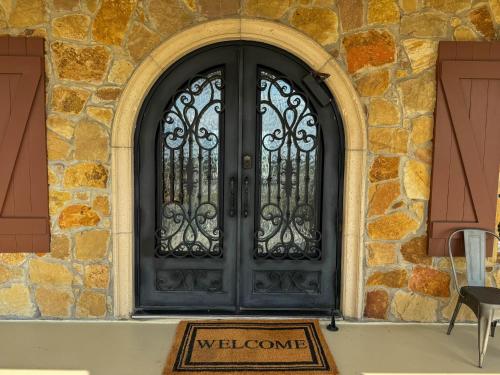 a black door on a stone building with a welcome sign at Bliss On The River in Llano