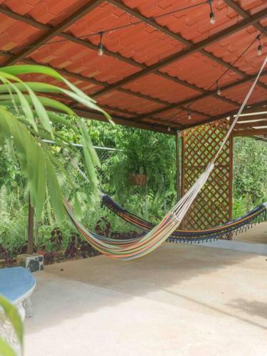 a hammock hanging from a patio under a roof at Private Villa with Pool near Manuel Antonio beach in Naranjito