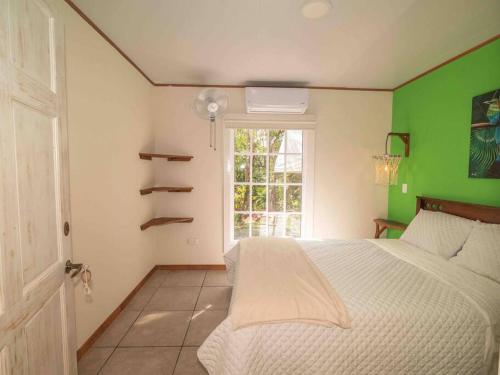 a bedroom with a white bed and a green wall at Private Villa with Pool near Manuel Antonio beach in Naranjito