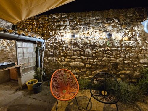 an orange fan and two chairs in front of a stone wall at Studio à louer à Villeneuve les Avignon in Villeneuve-lès-Avignon