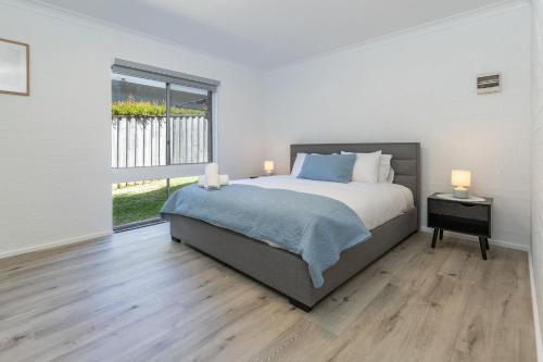 a white bedroom with a large bed and a window at Just Beachy in Boomerang Beach