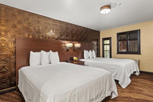 a hotel room with two beds with white sheets at Ellis Island Hotel Casino & Brewery in Las Vegas