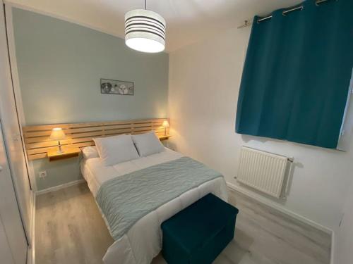 - une petite chambre avec un lit et un rideau bleu dans l'établissement La Douce Escale, à Carcassonne