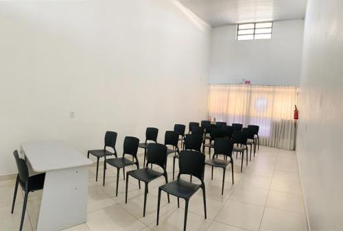 Una sala de conferencias con sillas negras y una mesa blanca. en OK Inn Hotel Criciúma, en Criciúma