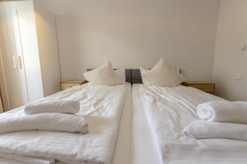 two beds in a room with white sheets and towels at Hotel Doerenkamp - Digital Access in Düsseldorf