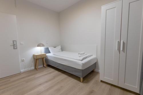 a white bedroom with a bed and a night stand at Hotel Doerenkamp - Digital Access in Düsseldorf