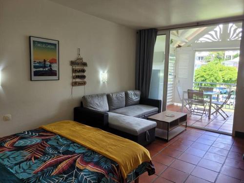 a bedroom with a bed and a couch and a patio at Grand studio les pieds dans l'eau! in Saint-François