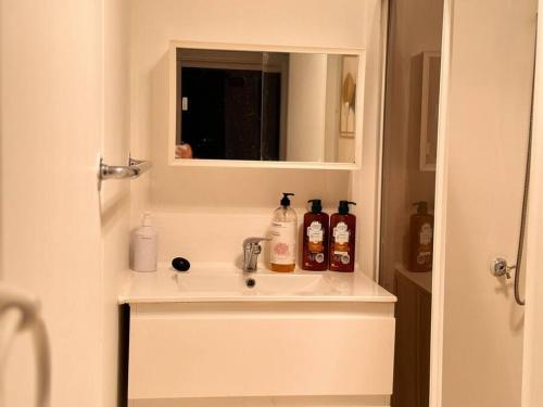 a bathroom sink with two bottles of soap and a mirror at Fairyland Getaway- at Central Coast with XXXL hot Jacuzzi & Fun - Round pool table and Slide bunk bed in Narara