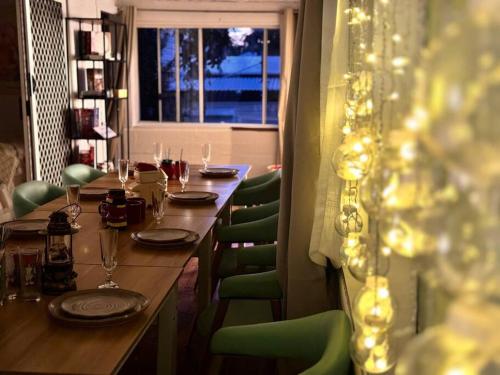 a long wooden table with green chairs and a window at Fairyland Getaway- at Central Coast with XXXL hot Jacuzzi & Fun - Round pool table and Slide bunk bed in Narara