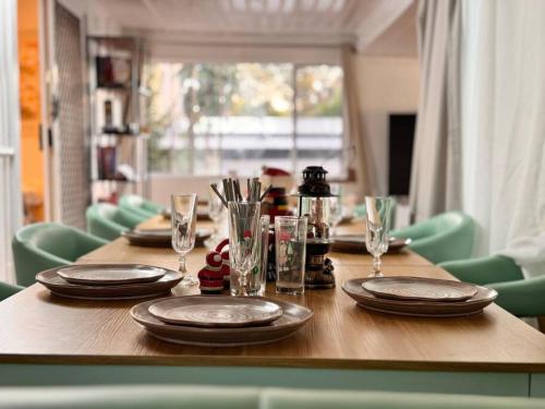 a wooden table with plates and glasses on it at Fairyland Getaway- at Central Coast with XXXL hot Jacuzzi & Fun - Round pool table and Slide bunk bed in Narara