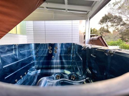 a blue tub in a house with a mirror at Fairyland Getaway- at Central Coast with XXXL hot Jacuzzi & Fun - Round pool table and Slide bunk bed in Narara