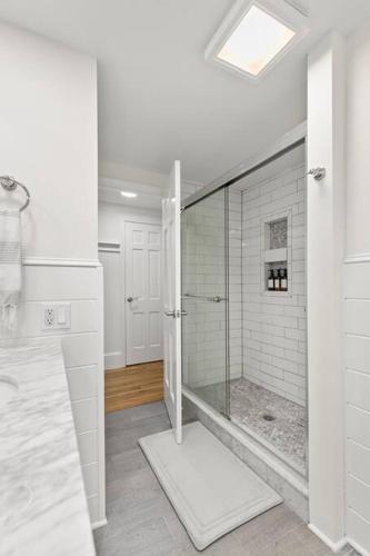 a white bathroom with a shower with a glass door at Retreat by the Hot Tub & Fire Pit, Dog-Friendly! in Brewster