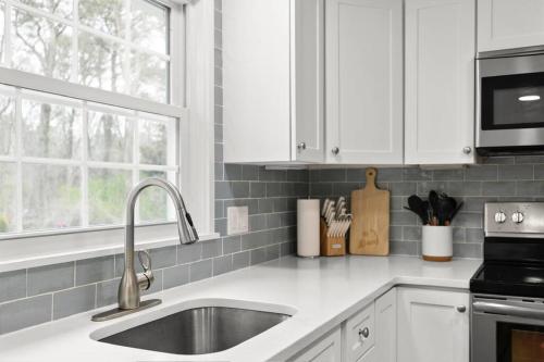 a kitchen with white cabinets and a sink at Retreat by the Hot Tub & Fire Pit, Dog-Friendly! in Brewster