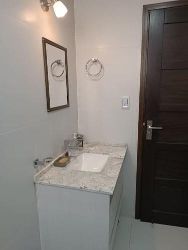 a white bathroom with a sink and a mirror at Apartamento cómodo y completo cala cala in Cochabamba