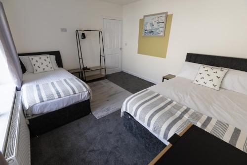 a small room with two beds and a mirror at Charming House - 3 minute's walk to the beach - Free Parking, Smart TV and Fast Wifi by Yoko Property in Redcar