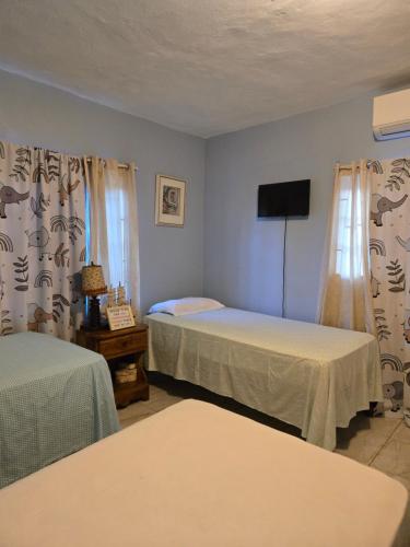 a room with two beds and a flat screen tv at Eve's Rockaway Villa in Alligator Pond Village