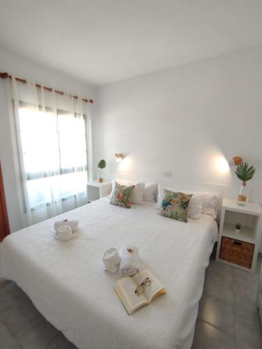 a bedroom with a large white bed with towels on it at Bungalow Capri Maspalomas in San Bartolomé