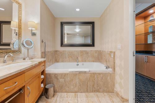 a bathroom with a tub and a sink and a mirror at TRUMP 56th Floor - Sphere and Strip View - No Resort Fees in Las Vegas