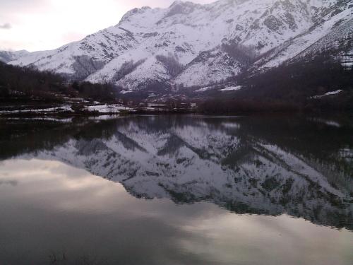 a reflection of a snow covered mountain in a lake at Casa de Aldea El Torrexon in Villamorey