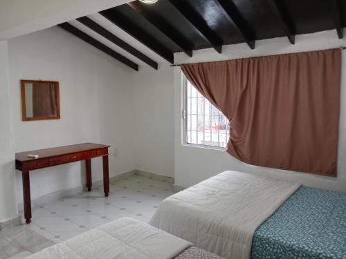 a bedroom with two beds and a desk and a window at Hostal Dream gunther in Cancún